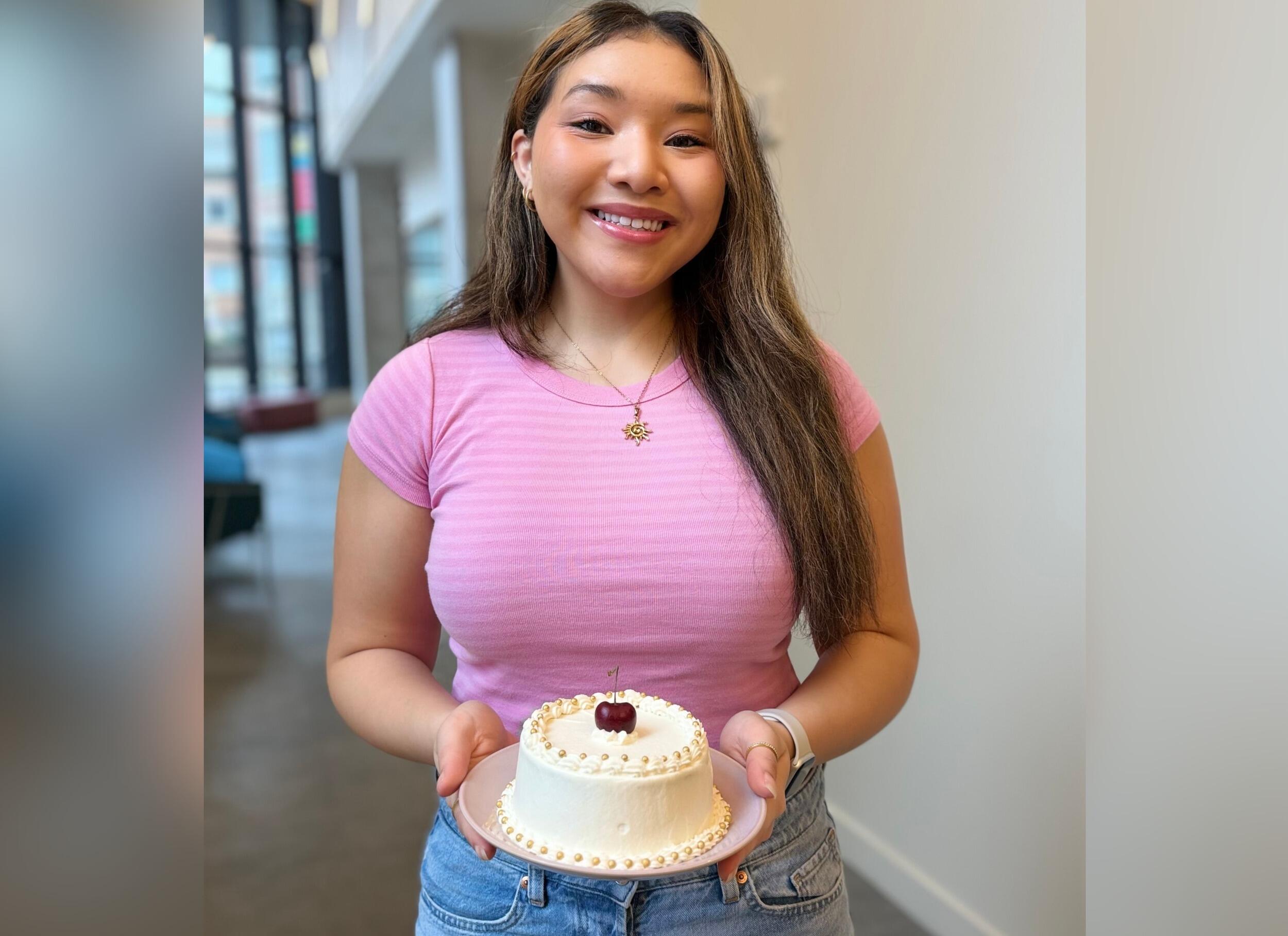 A photo of a woman holing a cake and smiling 