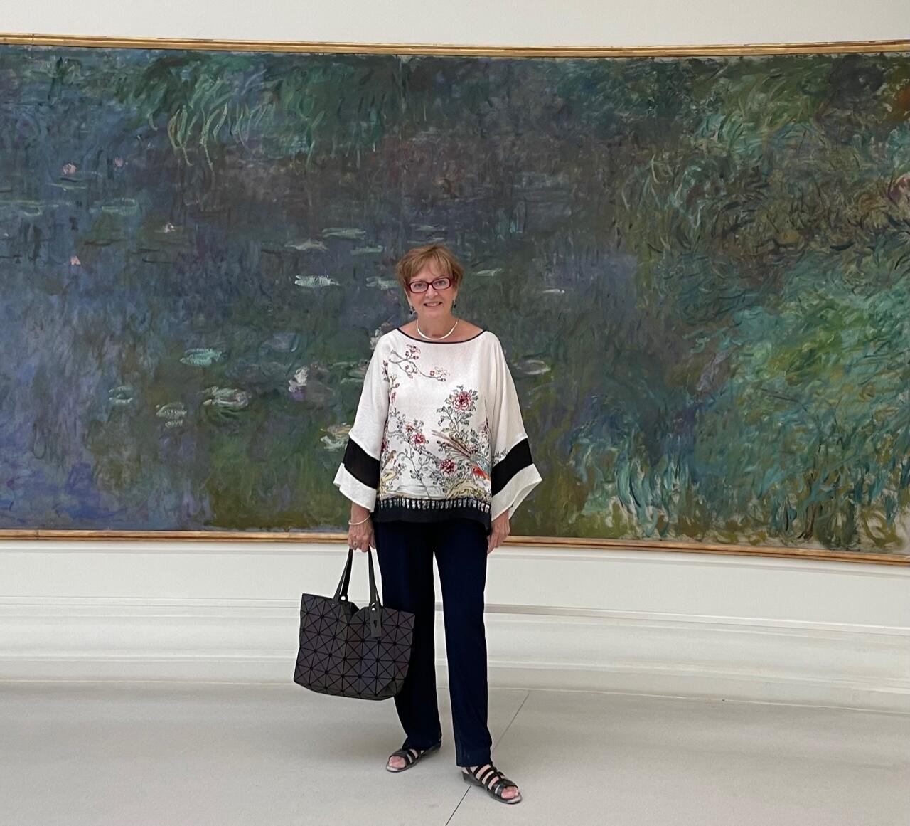 A woman standing in front ofa blue and green painting 