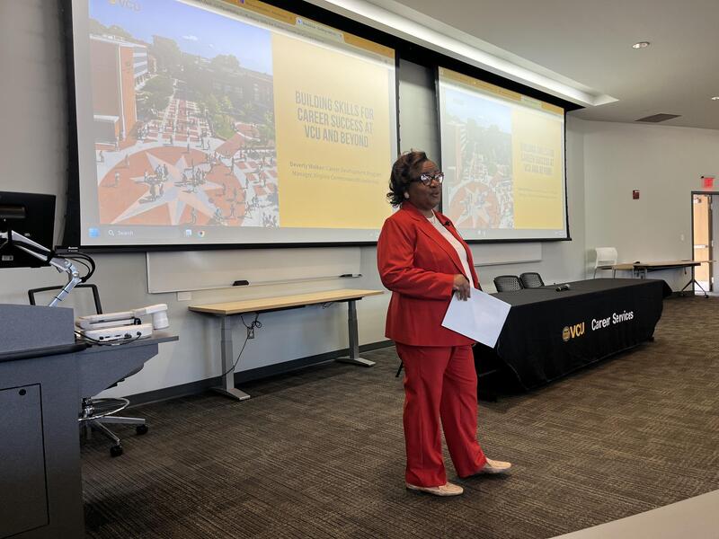 A photo of a woman standing at the front of a lecture room. 