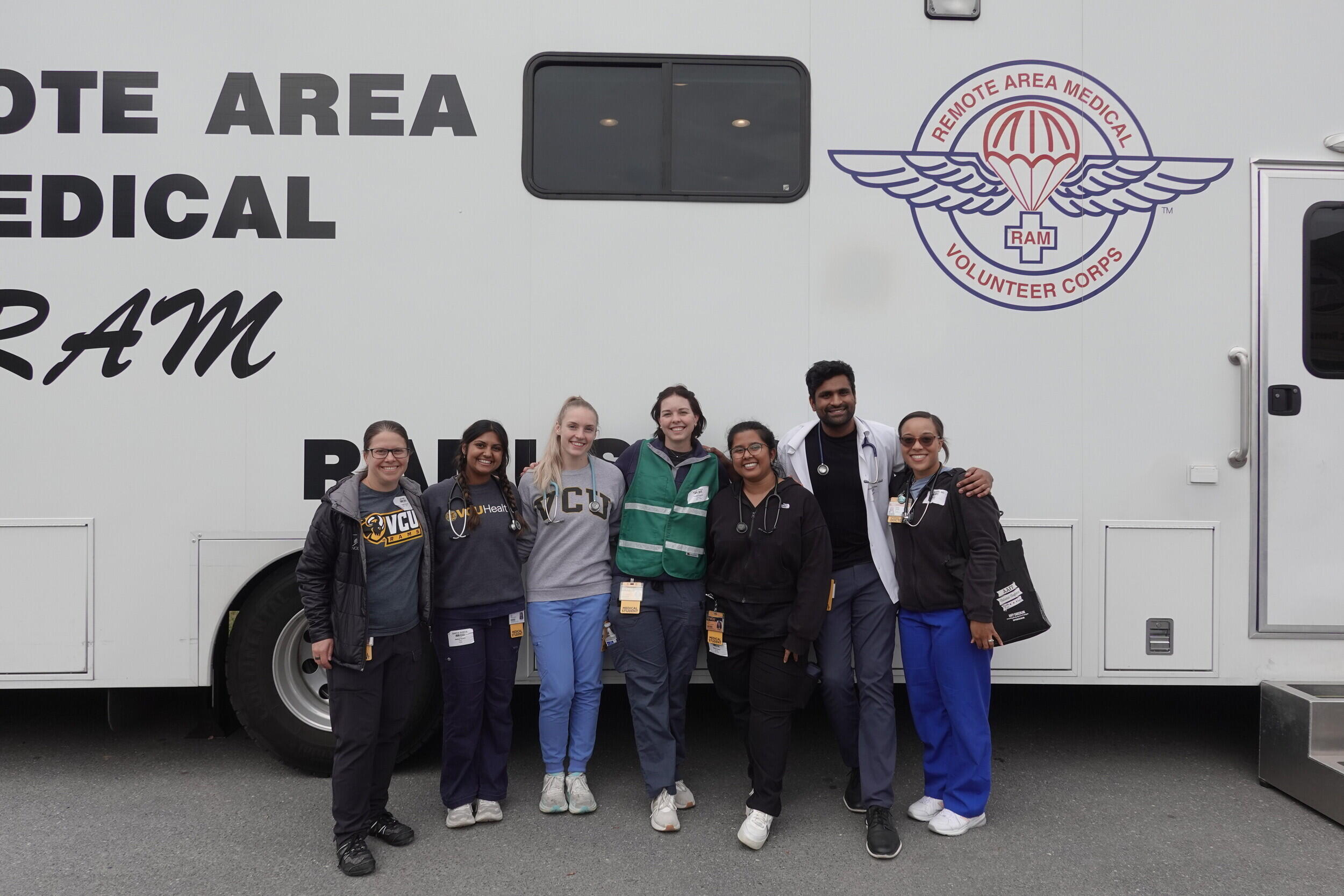 A group photo of seven people standing in front of a trailer. 