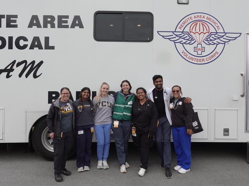 A group photo of seven people standing in front of a trailer. 