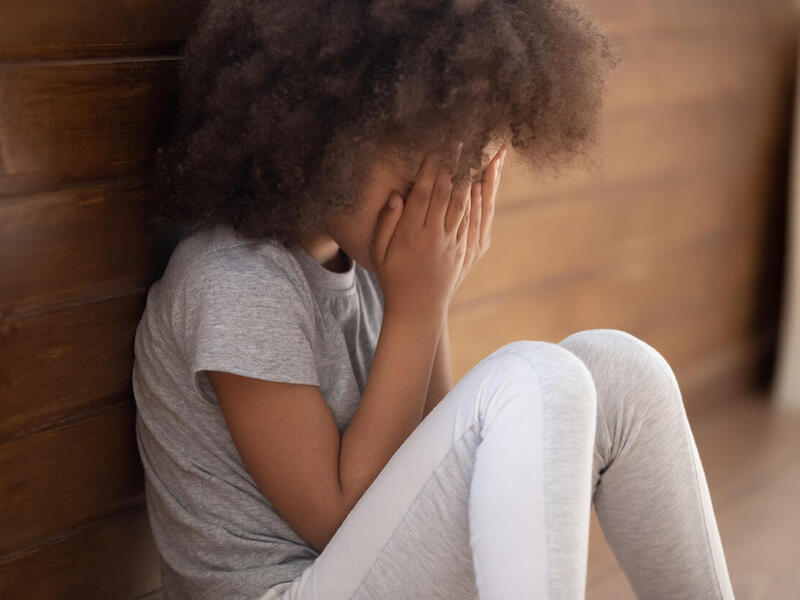 A person sitting covering their face with their hands.