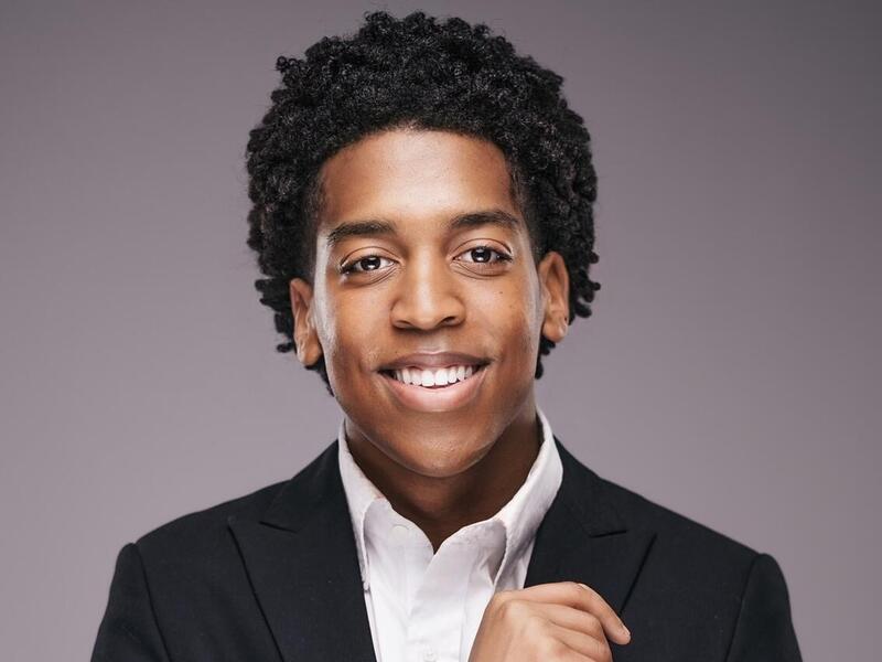 A photo of a man wearing a white button up shirt and a black sports coat. 