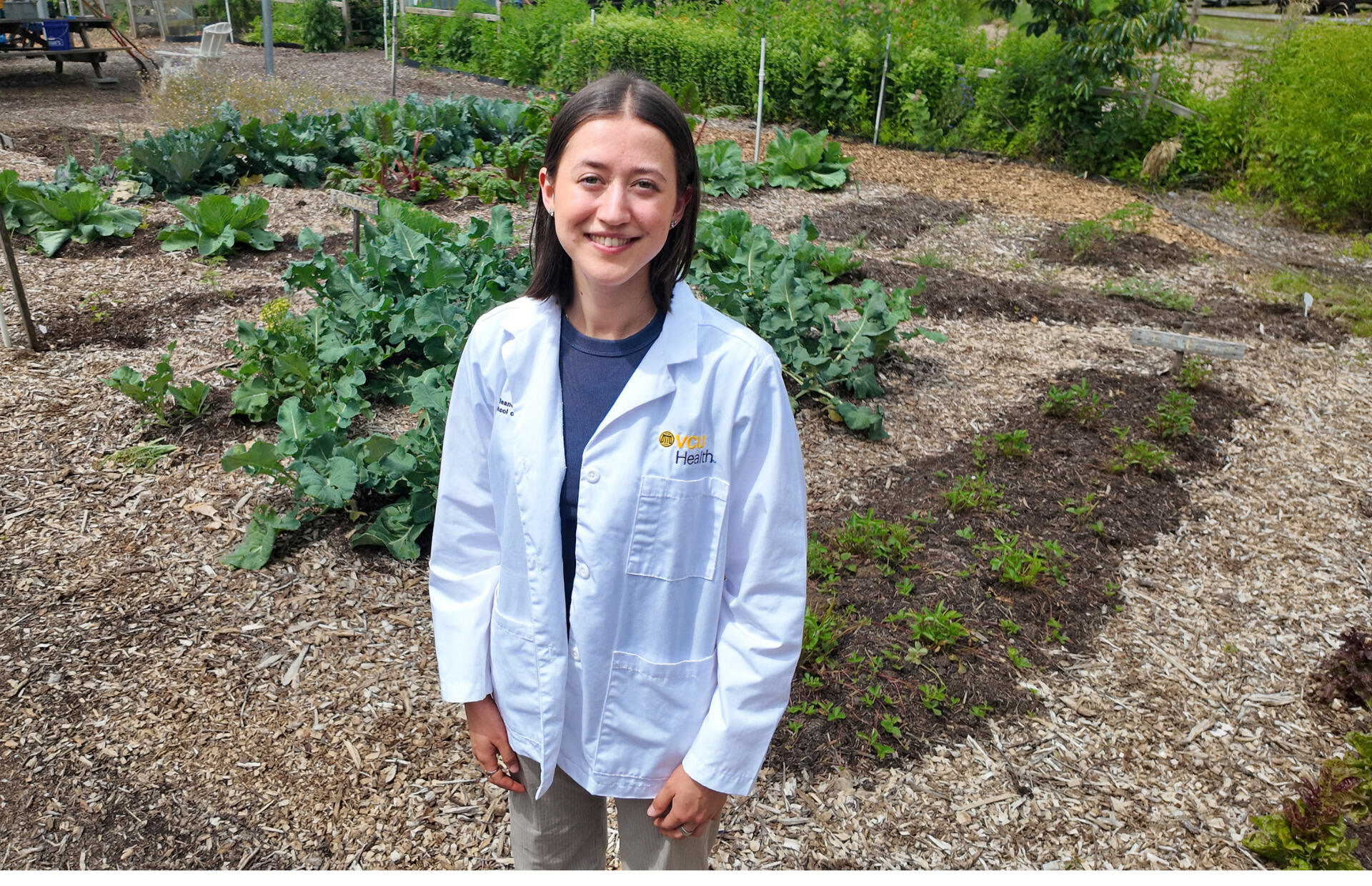 A photo of a woman wearing a white medical coat that says 
