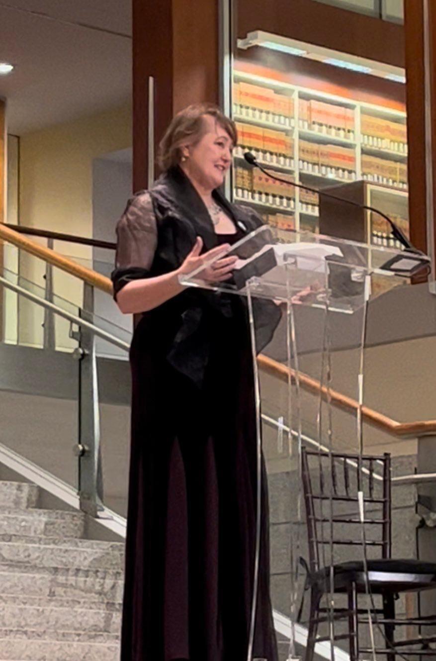 A woman wearing a black gown peaking at a podium 