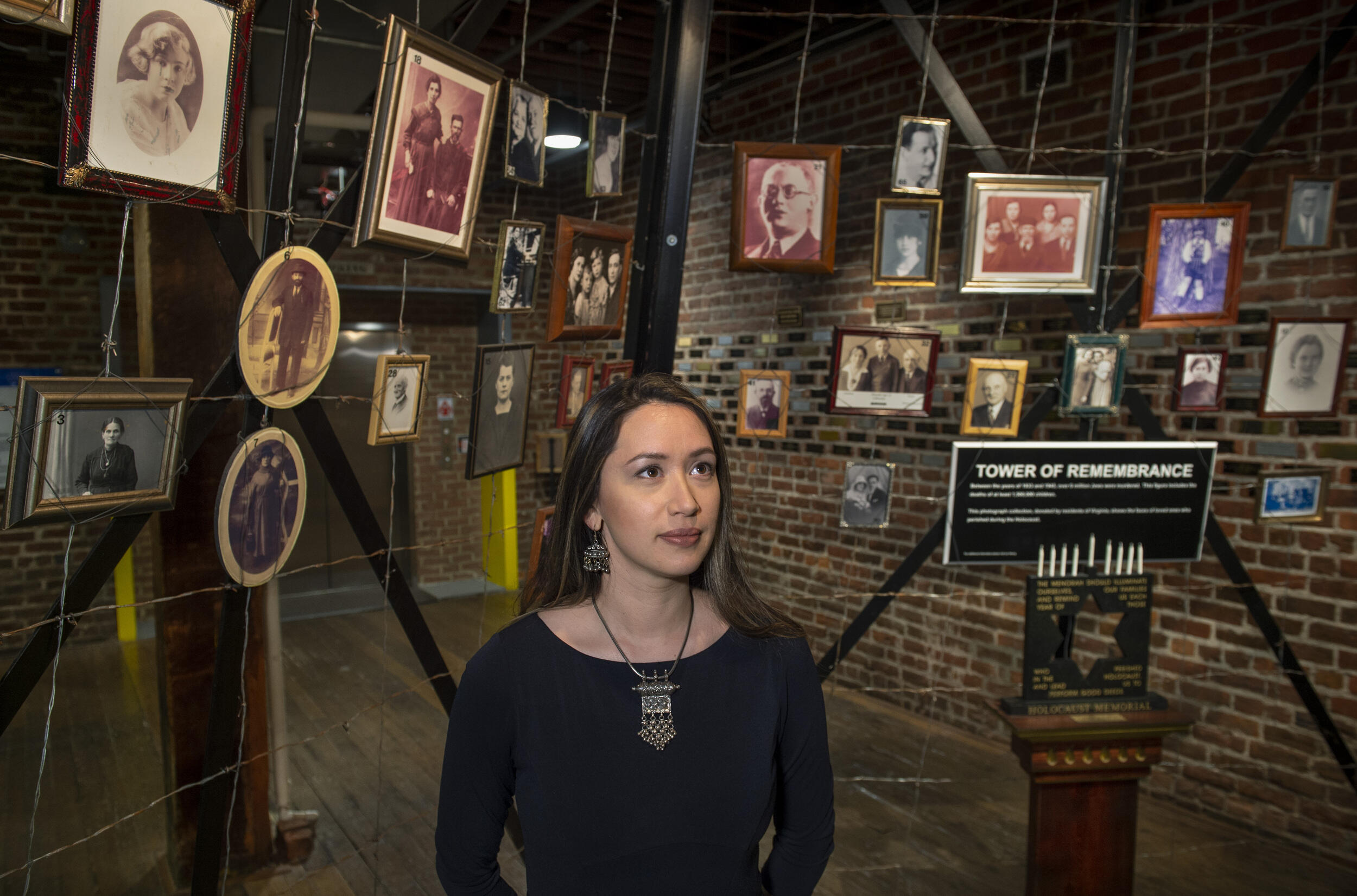 Jessica Trisko Darden standing in front of a series of picture frames with old portraits in them 