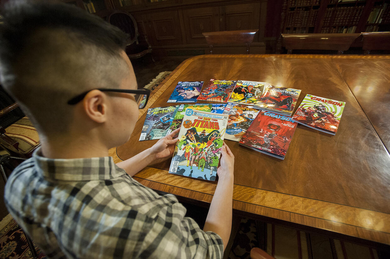 Thea Cheuk sitting at a table, holding a comic book