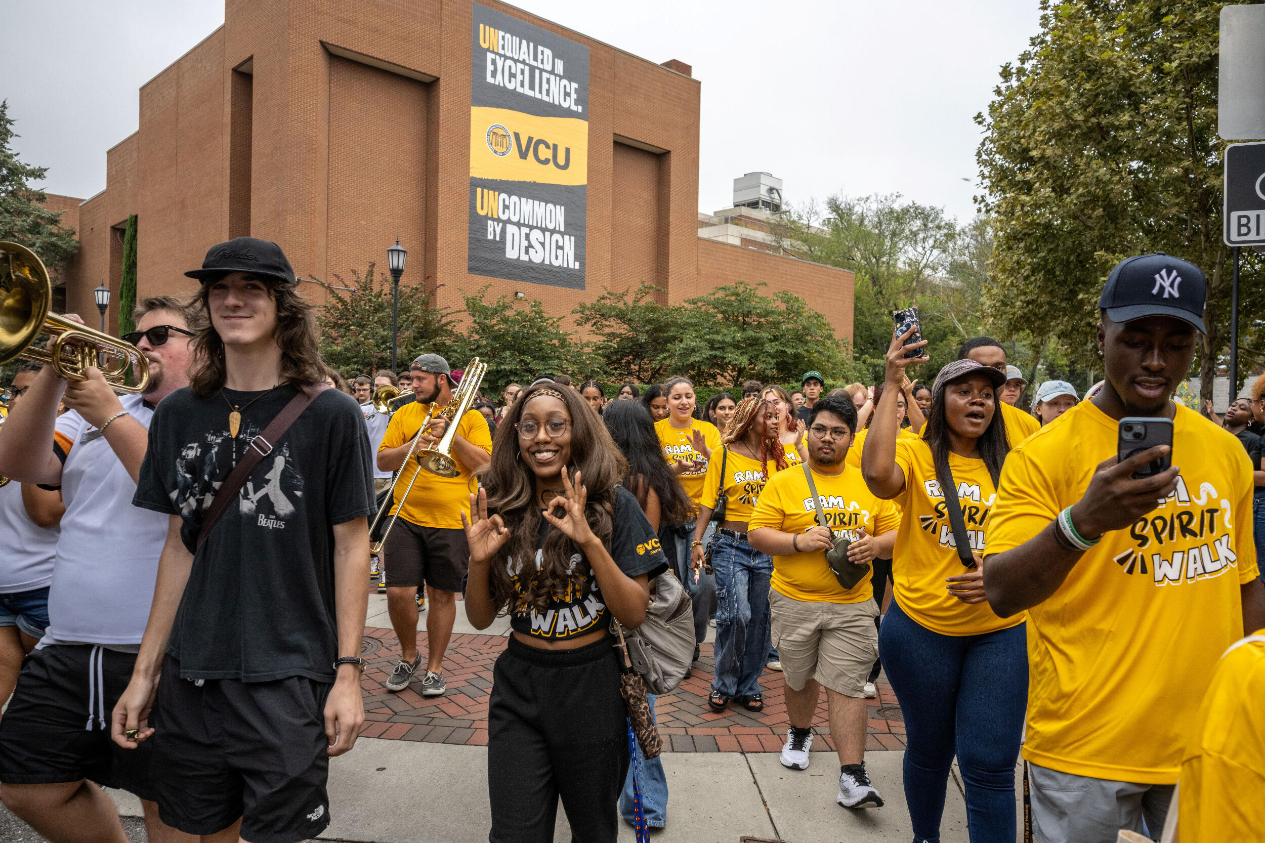 A crowd of men and women walk through a plaza.