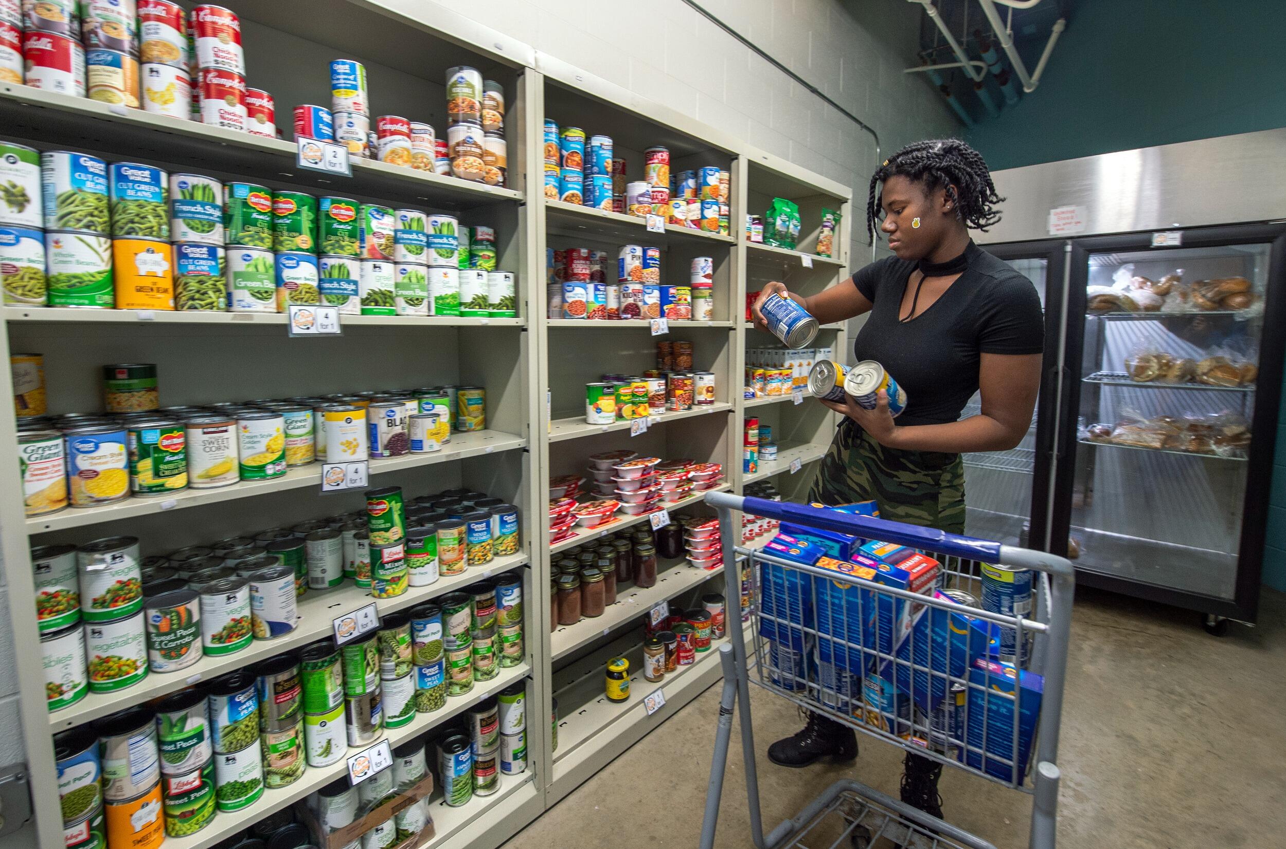 A student helps stock shelves of canned goods in the Ram Pantry.