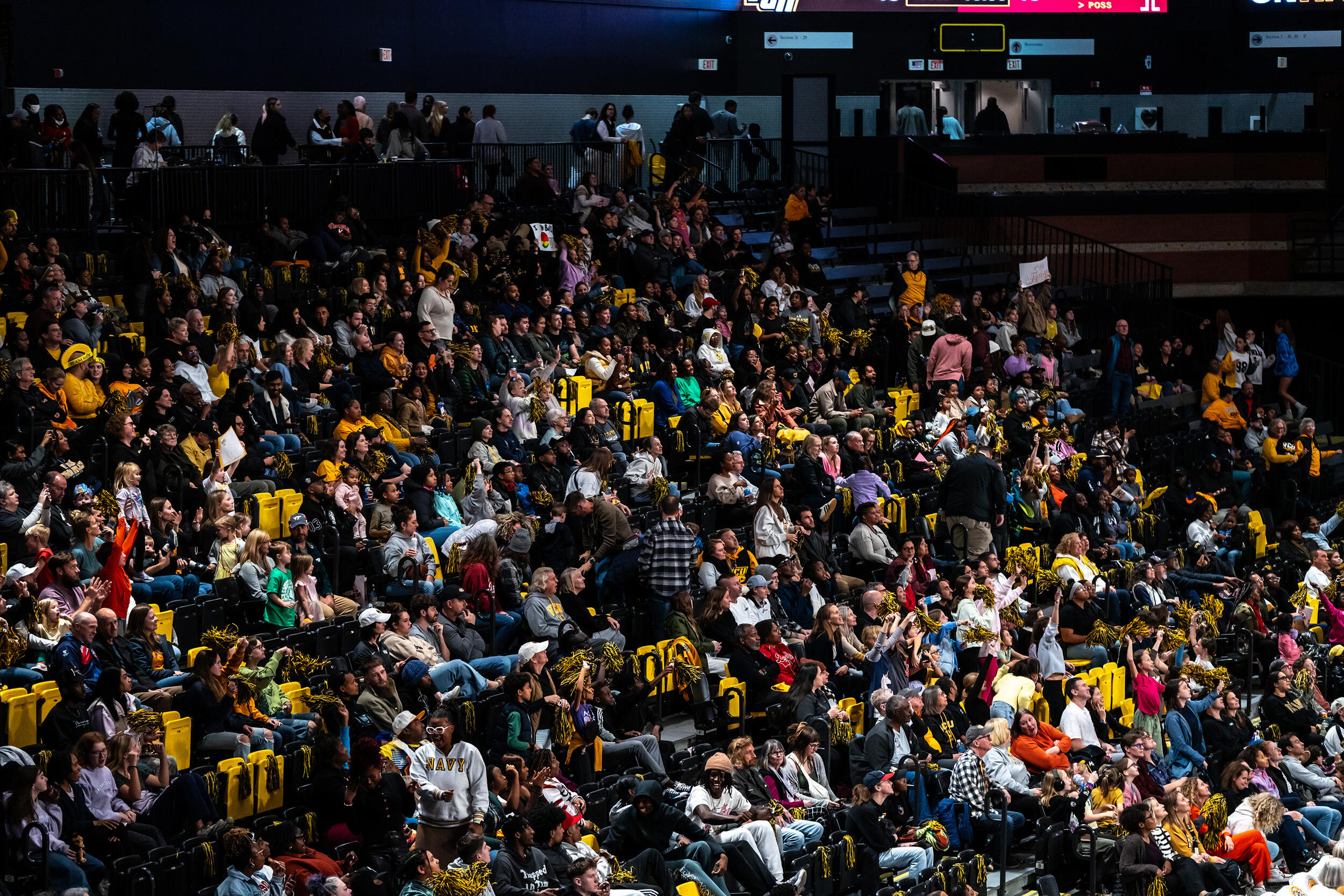 A photo of a crowd of people sitting in the stands at a basketball game. 