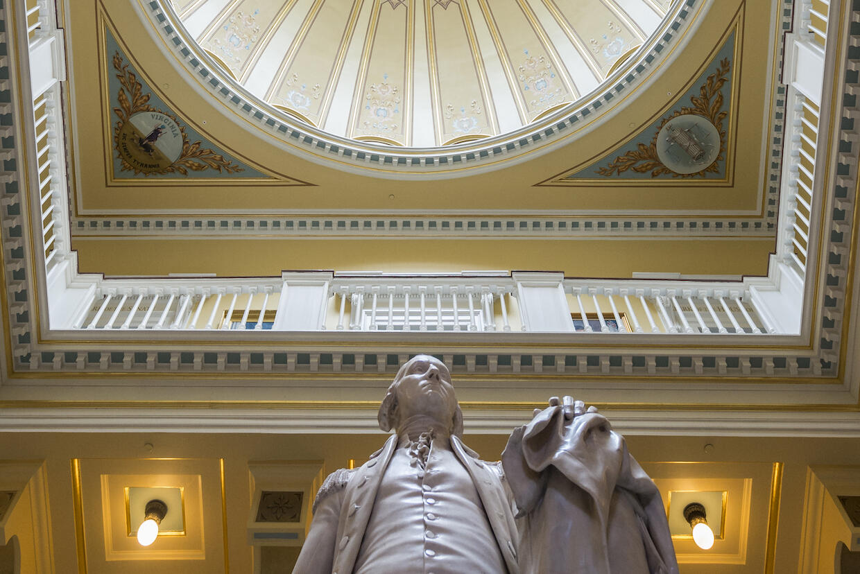 A statue sits underneath the rotunda of a building.