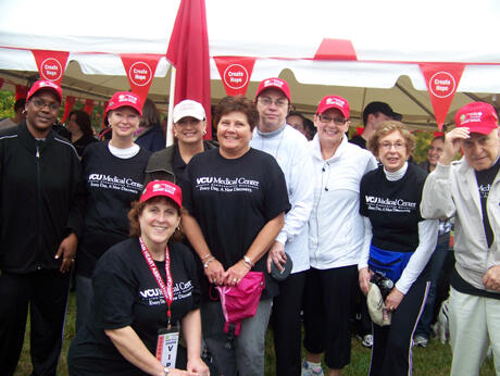 Barbara Harding, VCU Ambulatory Care Center nurse manager and team captain, kneels in front of the ACC team. From left: Francis Robinson, ACC 4 Adult Medicine Specialties; Paula Simpson, R.N., nurse case manager, Stony Point Spine Center; Susan Chandler, ACC nurse clinician; Pam McLaughlin, ACC financial analyst; Darlene Brink Stephens, ACC 4 Adult Medicine Specialties, Infusion Center; Suzanne Schroeder, ACC 4 Adult Medicine Specialties; Ellen Gerszten, ACC adult medicine and adult medicine specialties; and Enrique Gerszten, survivor. Photo by Laura Savage