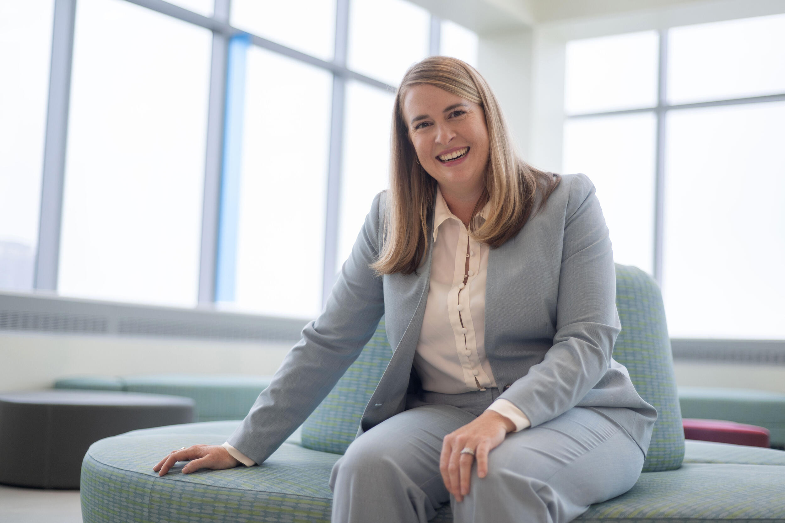 A photo of a woman sitting on a plush circle shaped couch. 