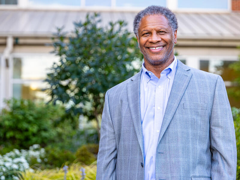 A phot of a man from the waist up standing outside. 