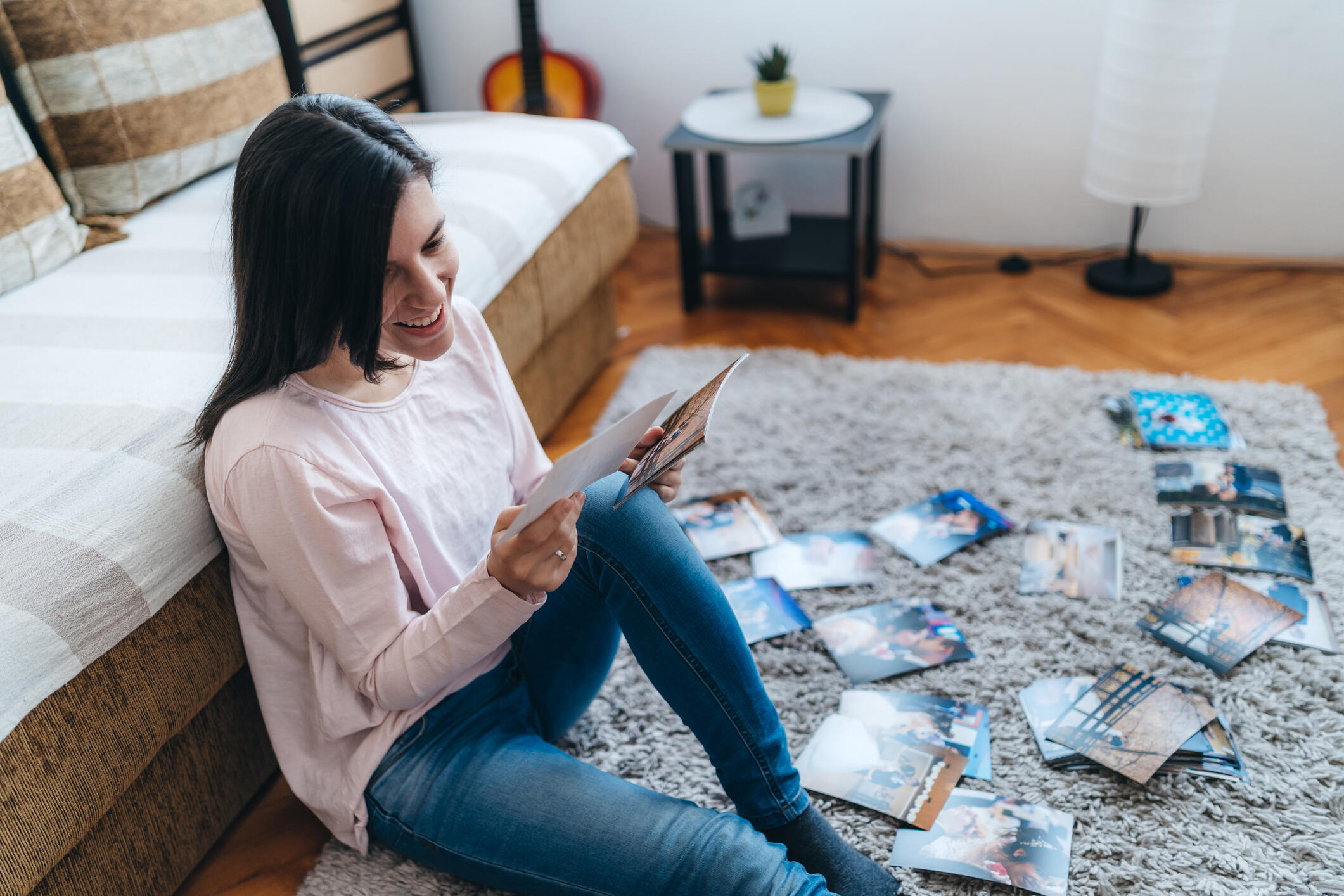 A photo of a woman sitting on the floor, smiling and looking at photos. 