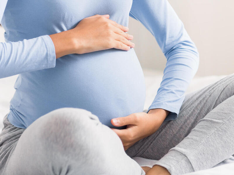 A pregnant woman cradles her stomach.