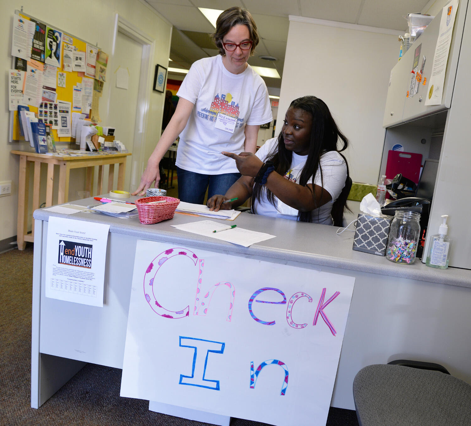 Alex Wagaman, Ph.D., assistant professor in the School of Social Work, and Advocates for Richmond Youth member Tiffany Haynes greet people at the check-in table for the pop-up drop-in center at Side By Side.
