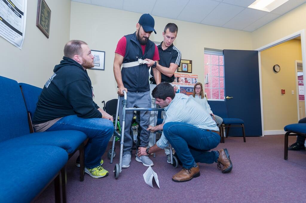 Delano and Ward work with a patient who has a spinal cord injury as Fosdick offers guidance and suggestions.
