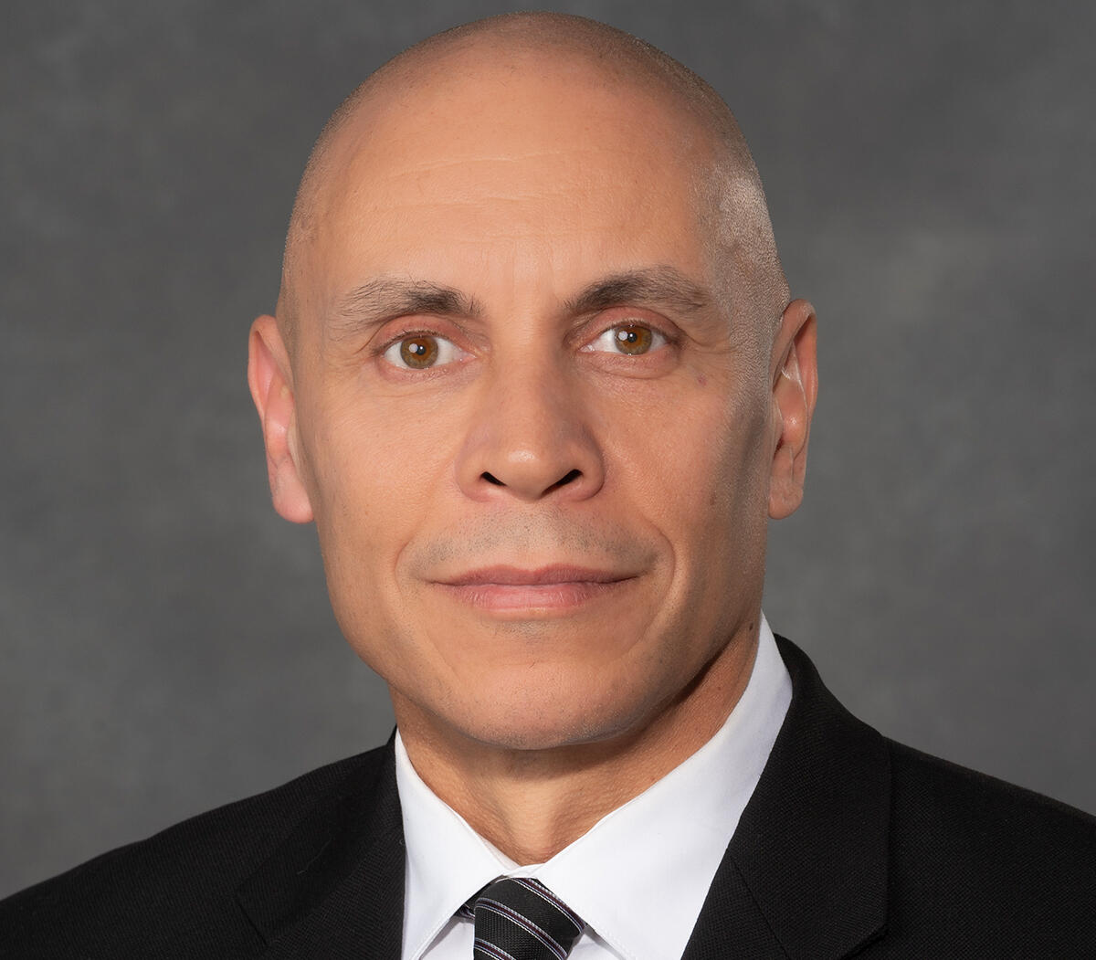 A photo of a bald man wearing a suit and tie from the shoulders up. 