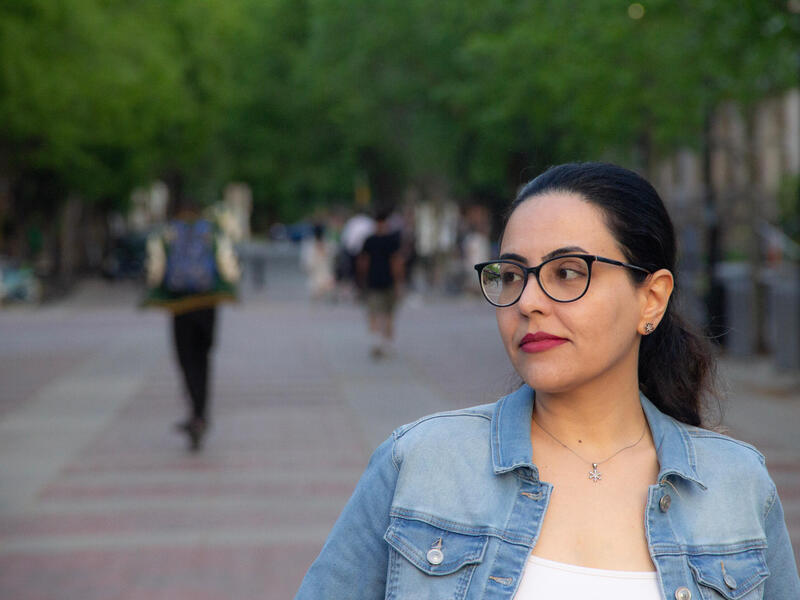 A woman in glasses walks down a walkway.