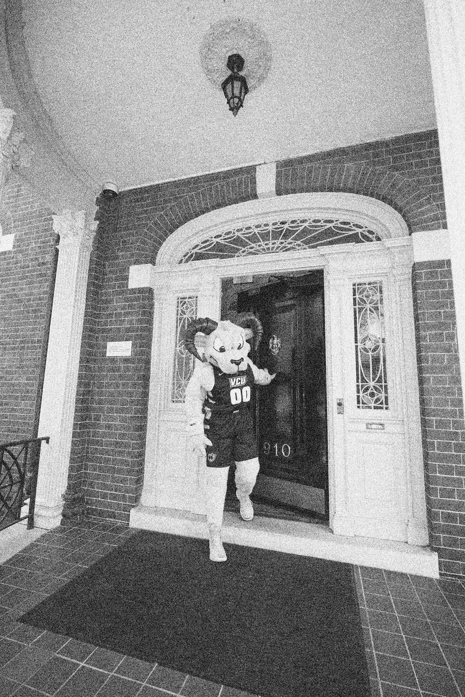 A person in a ram costume walking out of a front door. 