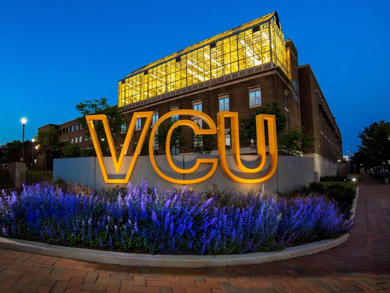 Lights shine on a gold VCU sign.