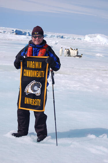 John Duval, CEO of MCV Hospitals, displays VCU pride during a recent visit to Antarctica over the recent holiday season. Duval's three-week trip culminated with a visit to nearly the southernmost tip of the planet. Native Emperor Penguins are in the background.
