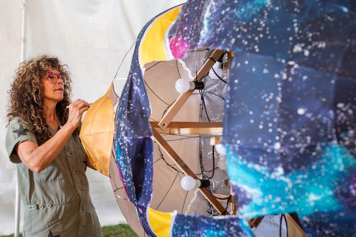 A photo of a woman working on a paper sculpture 