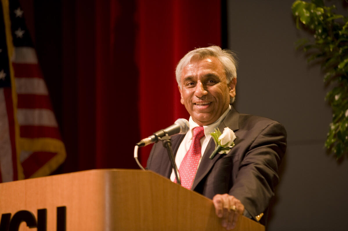A photo of a man wearing a suit and tie standing at a podium 