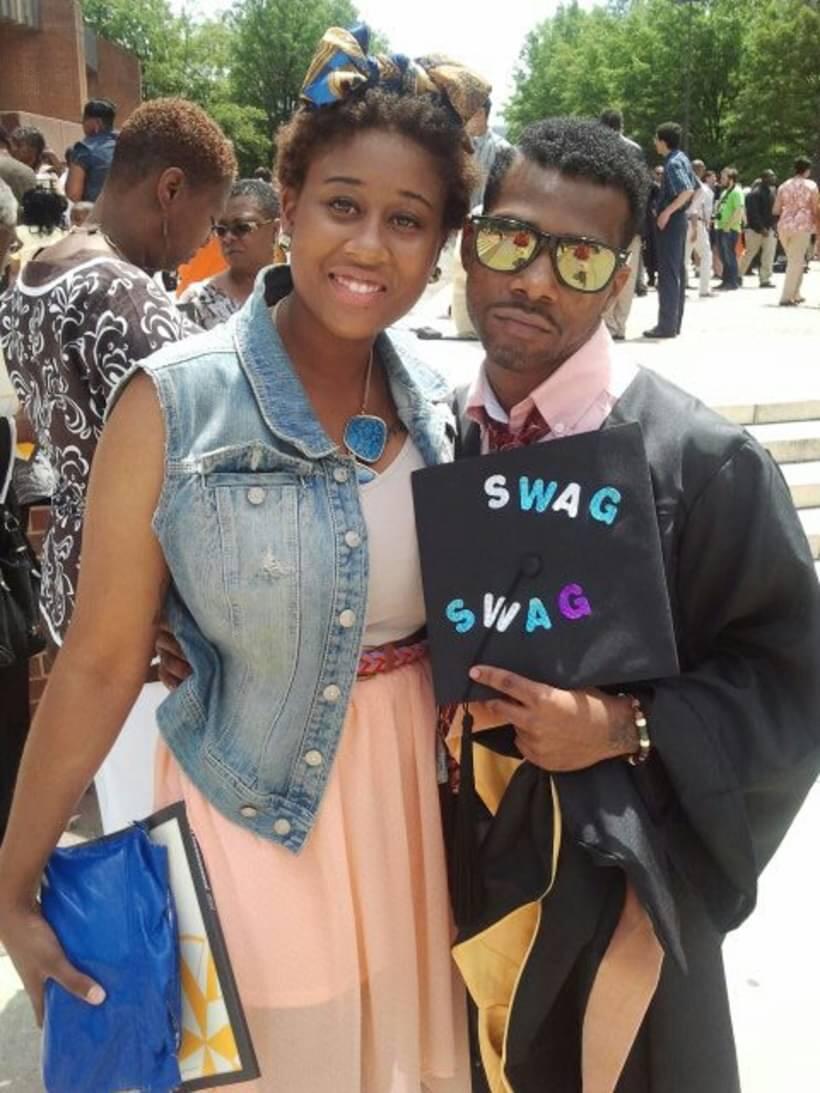 A photo of a mand and a woman standing next to each other. The man is holding a graduation cap that says \"swag swag\" in different colored letters. 