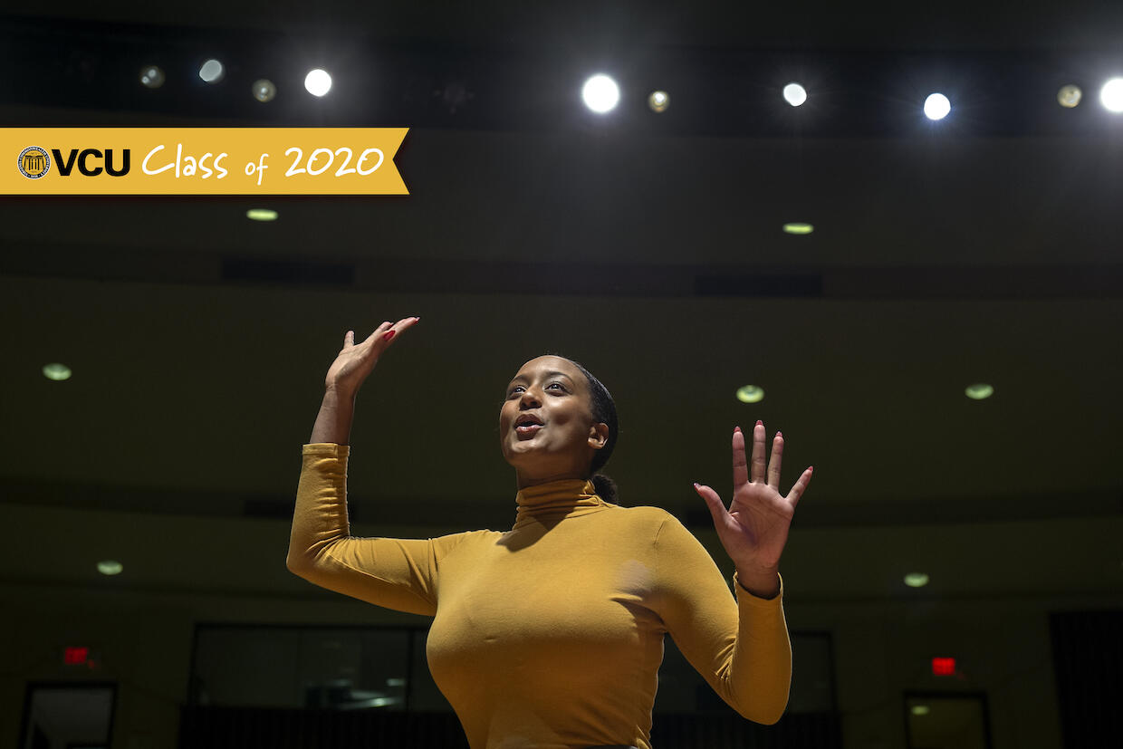 Amari Samya posing on a stage with spotlights in the background.