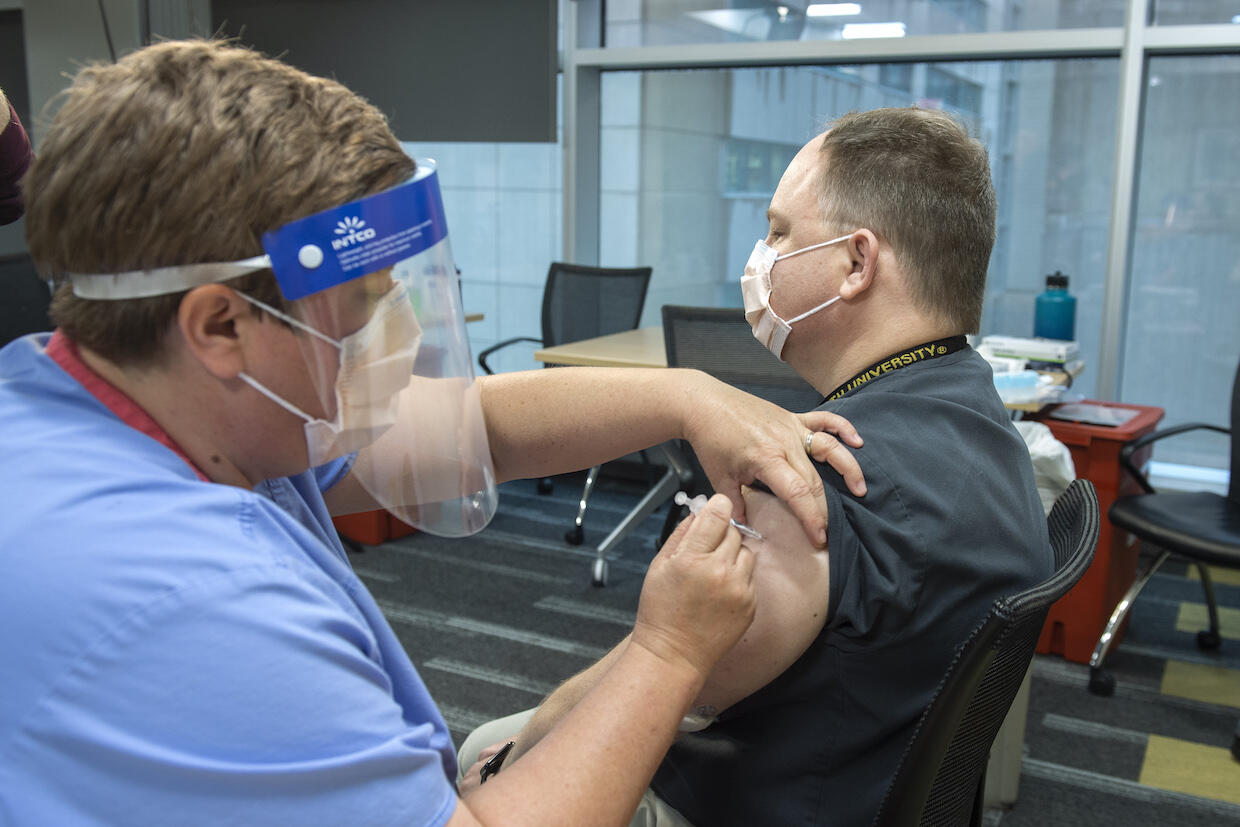 Emergency medicine physician Joel Moll, right, receives a COVID-19 vaccine at V C U Medical Center