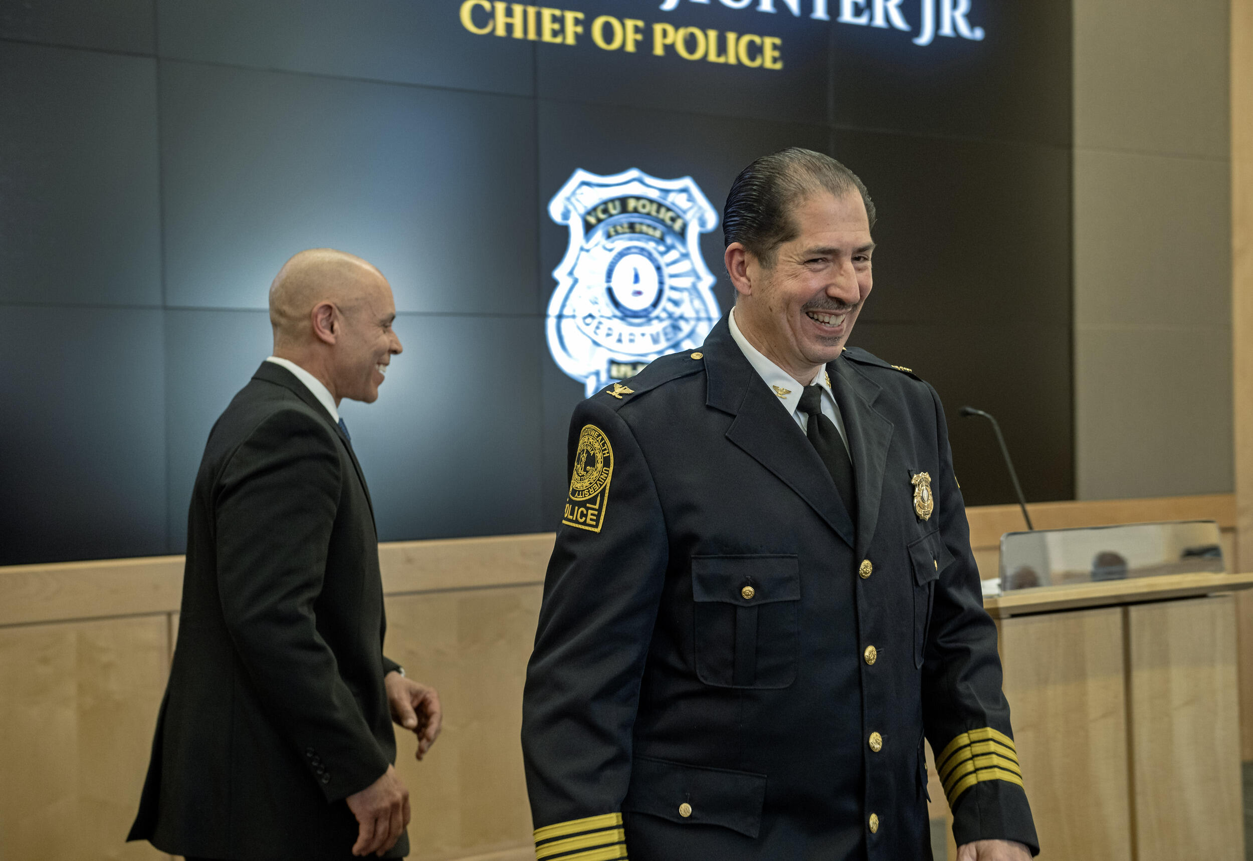 A photo of two men smiling and walking in opposite directions. 