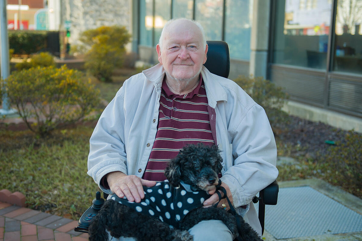 Dominion Place resident Floyd Roselli and his black poodle, Lucky, pose in front of Dominion Place. 