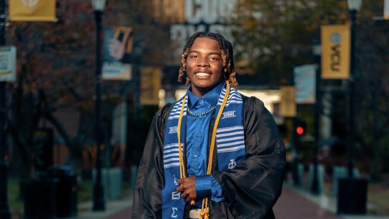A photo of a man wearing a graduation gown. 