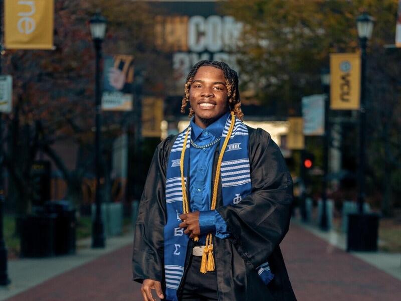 A photo of a man wearing a graduation gown. 