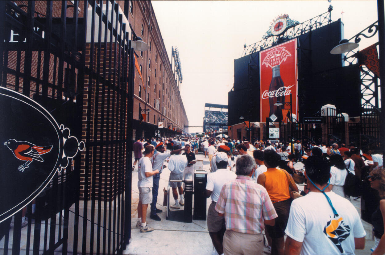 View of the pedestrian concourse at Oriole Park at Camden Yards, between a brick warehouse and the back of the right field stands