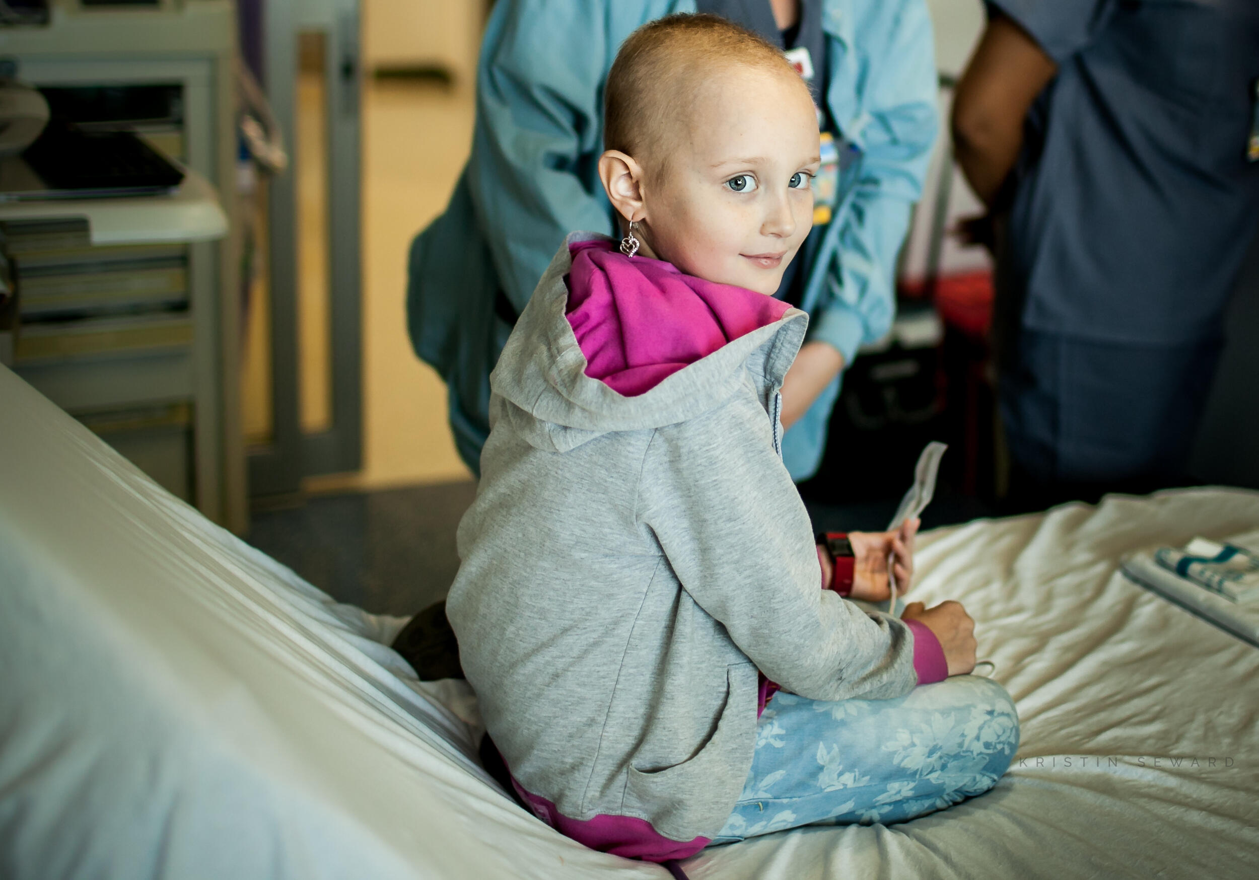 Young girl sits on a hospital bed.