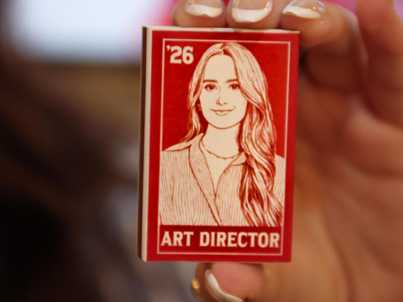 A red matchbox with a woman's image on it in white.