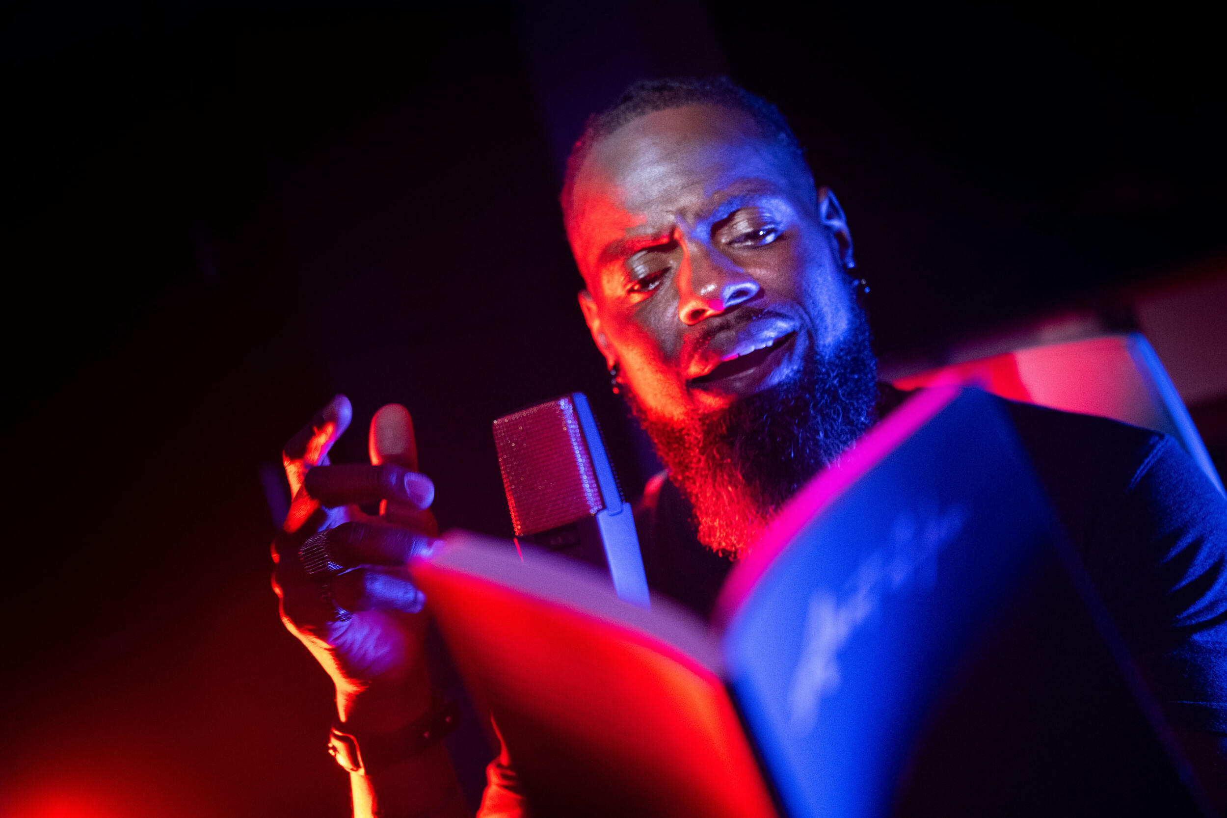 A man reads from a book, speaking into a microphone.